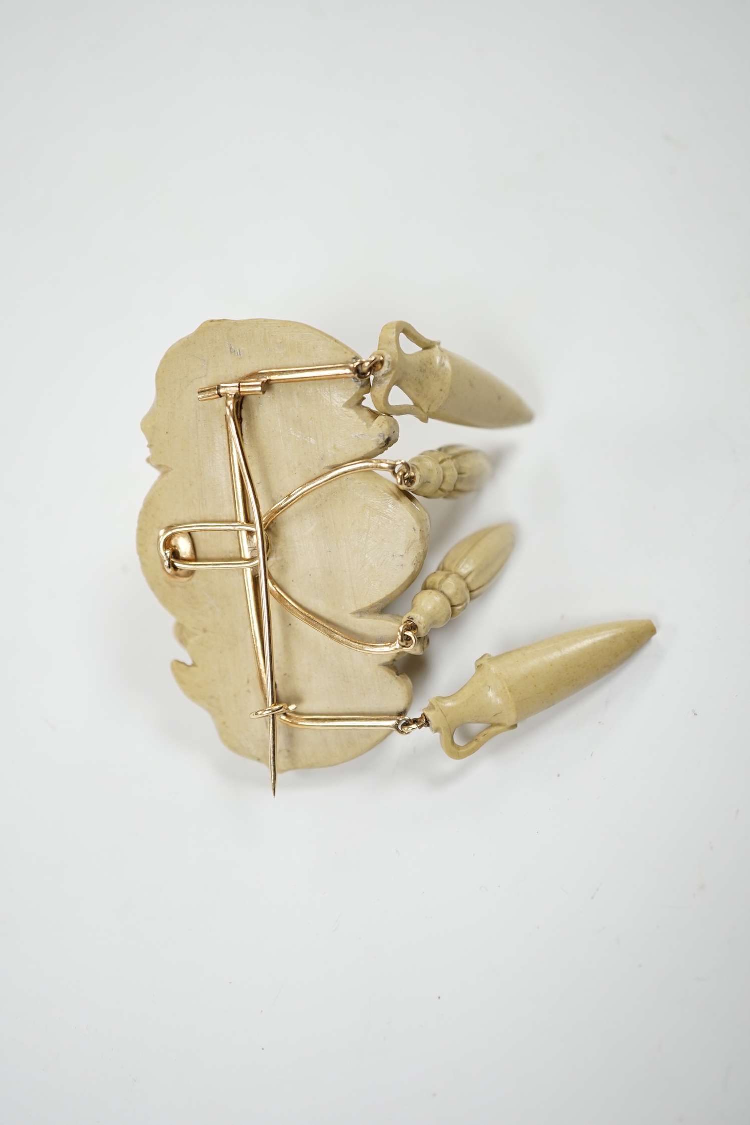A yellow metal mounted lava drop brooch, modelled as the head of a lady flanked by ram's heads, width 53mm.